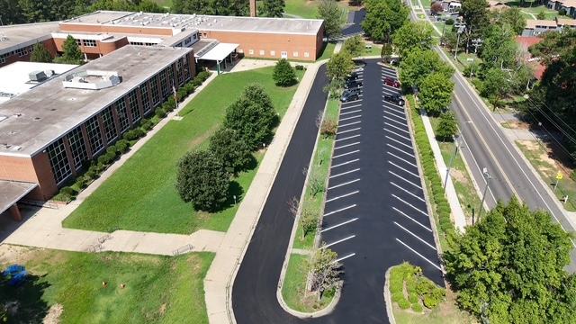 Repaved school parking lot with fresh striping, aerial view
